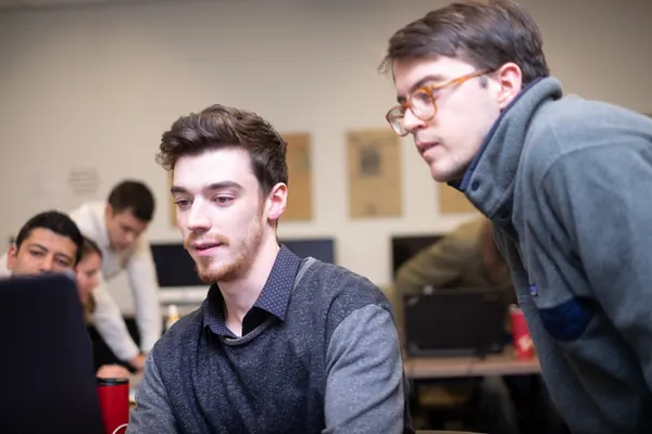 Michael at a computer in a newsroom, working with a colleague
