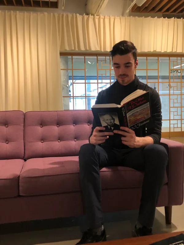 Michael reading a book on a pink sofa