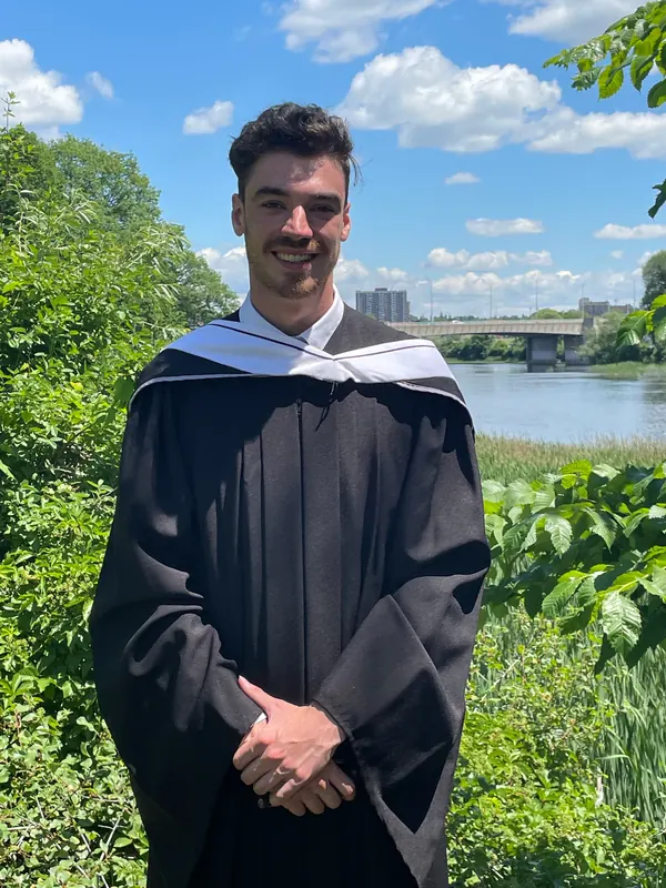 Michael A. Smith in a graduation gown by the river in Ottawa